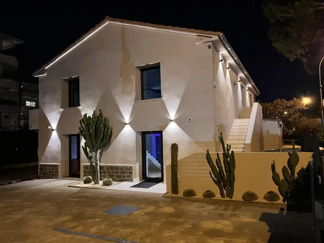 La façade du cabinet éclairée de nuit, cactus au premier plan